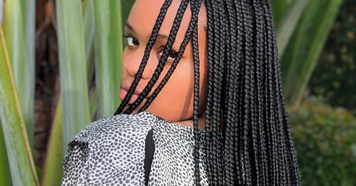 Back view of a woman with long knotless braids standing in a garden